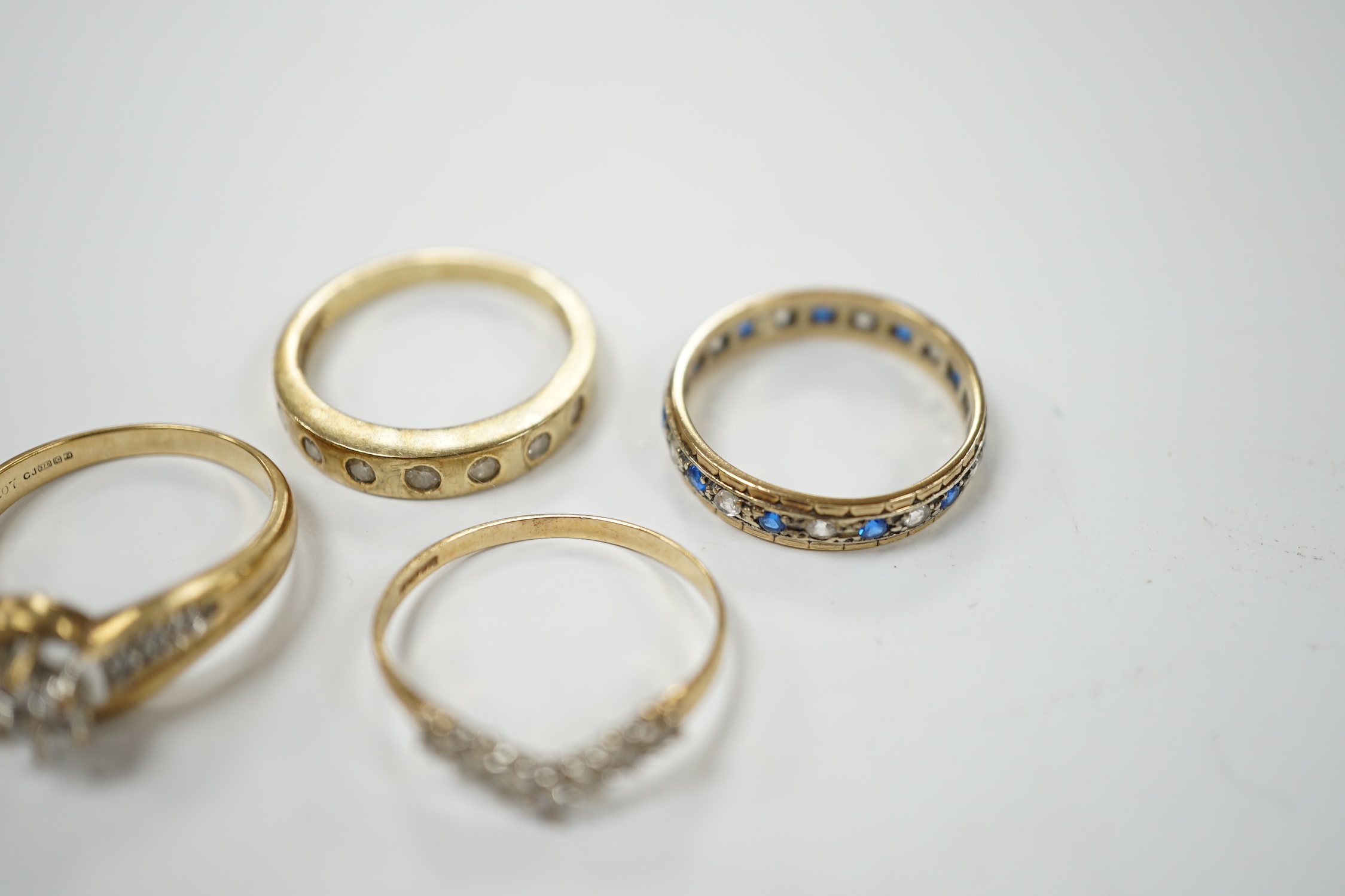 Two modern 9ct gold and diamond set rings and a 9ct gold, simulated diamond set chevron shaped ring and one other 9ct and paste set band, gross weight 9 grams. Condition - poor to fair